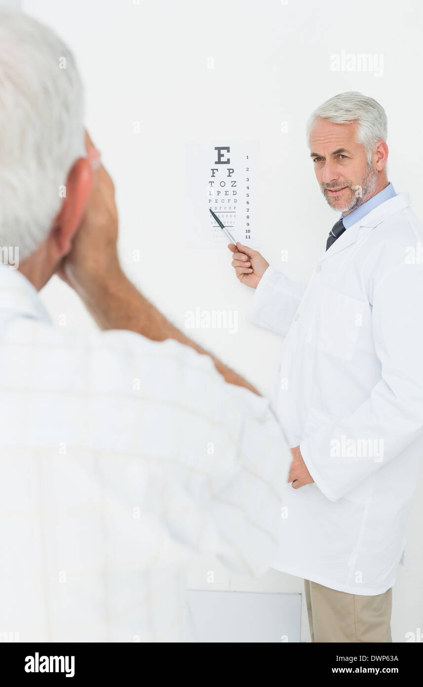 Pédiatre ophtalmologiste avec senior patient pointing at eye chart Banque D'Images