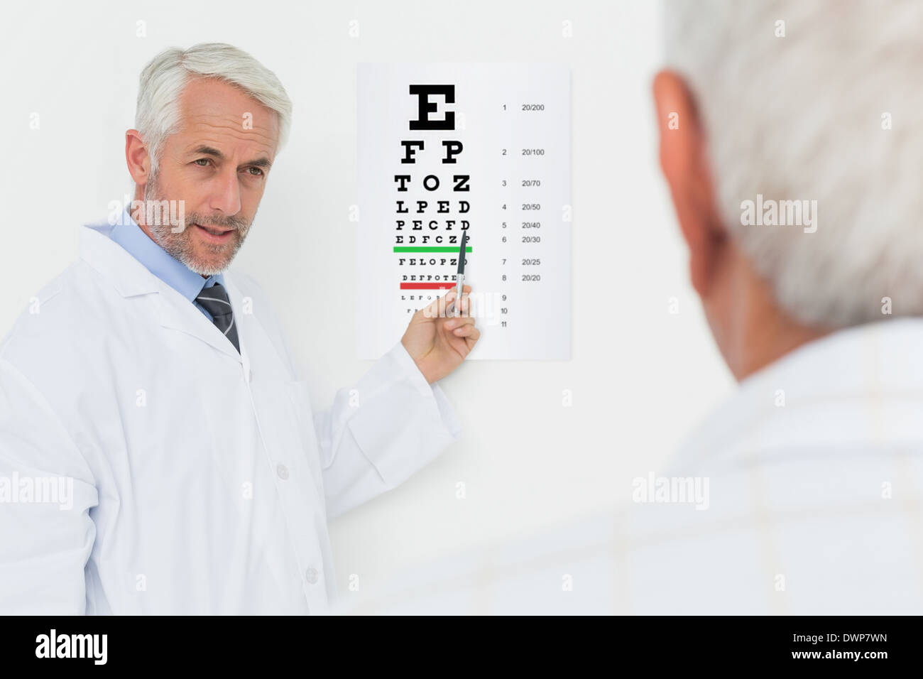 Pédiatre ophtalmologiste avec senior patient pointing at eye chart Banque D'Images