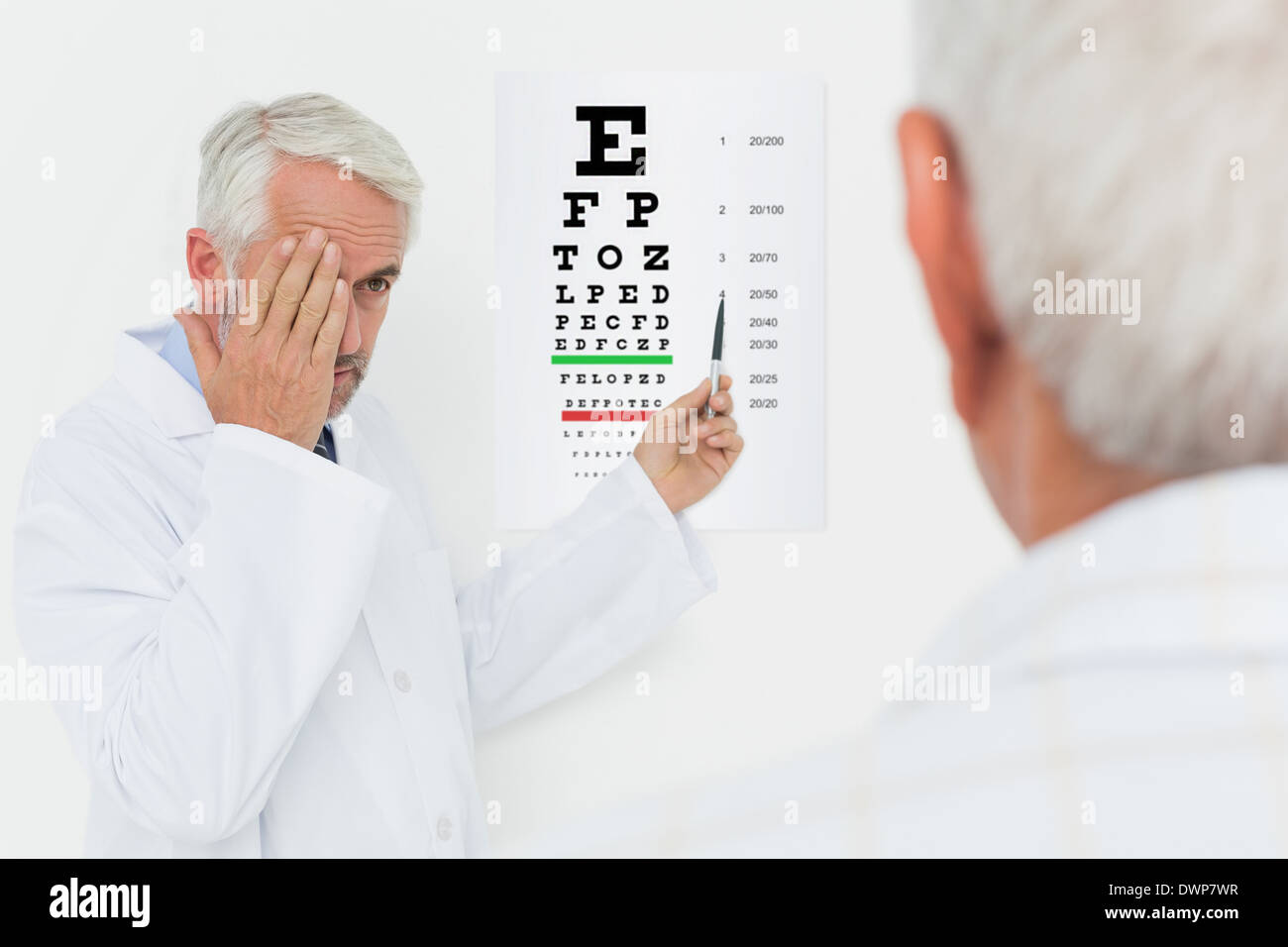 Pédiatre ophtalmologiste avec senior patient pointing at eye chart Banque D'Images