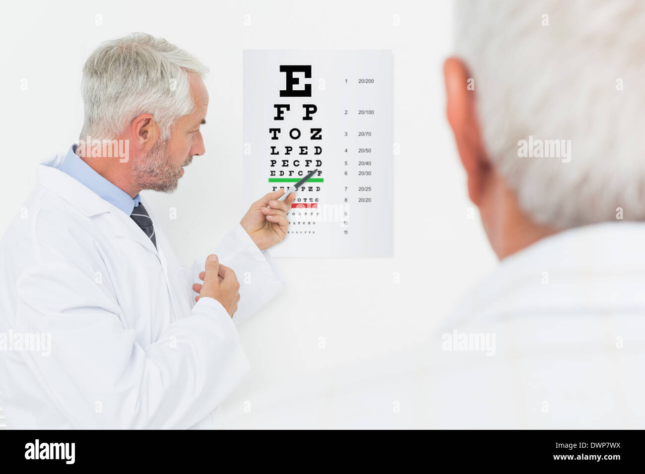 Pédiatre ophtalmologiste avec senior patient pointing at eye chart Banque D'Images