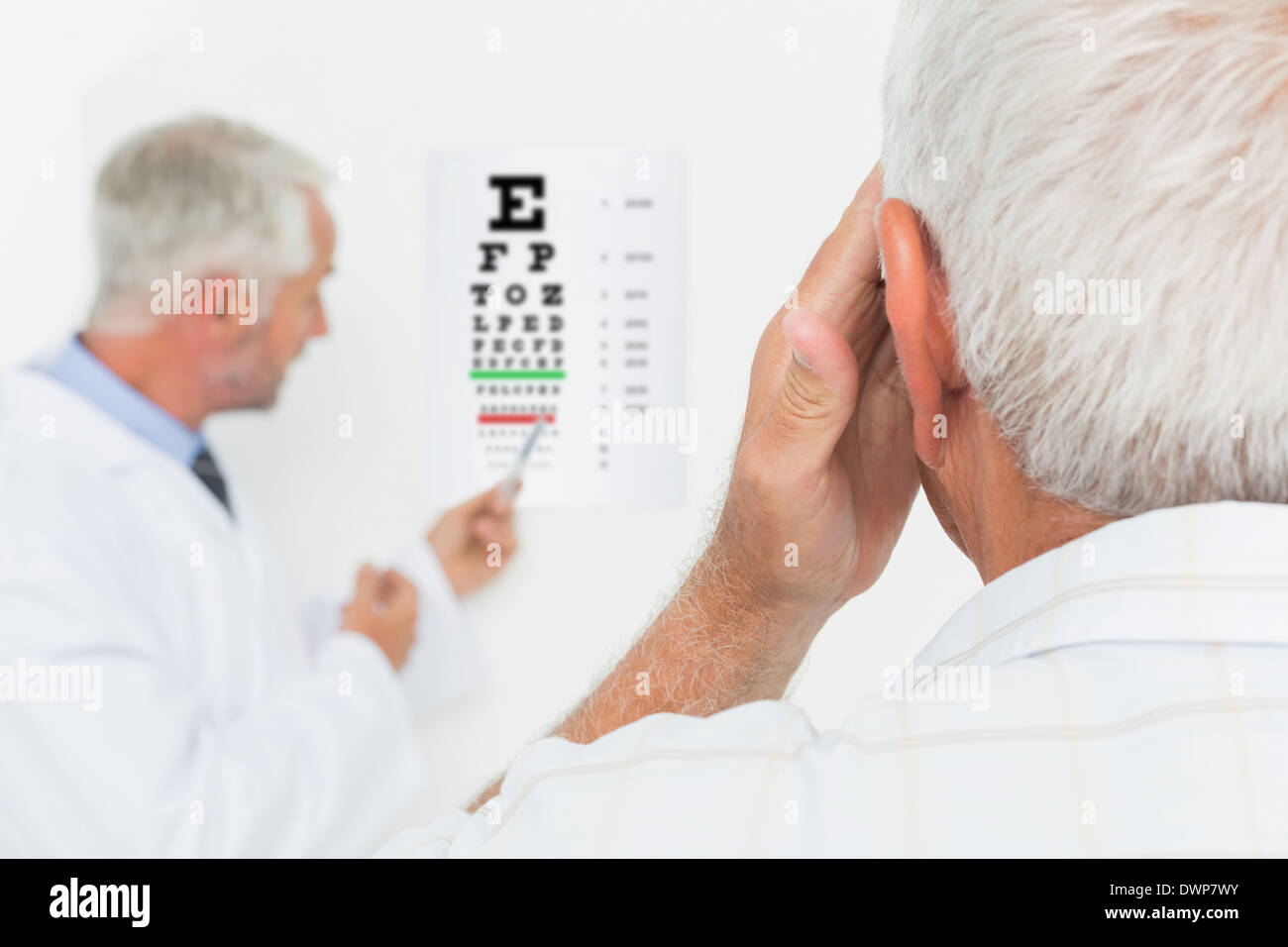 Pédiatre ophtalmologiste avec senior patient pointing at eye chart Banque D'Images