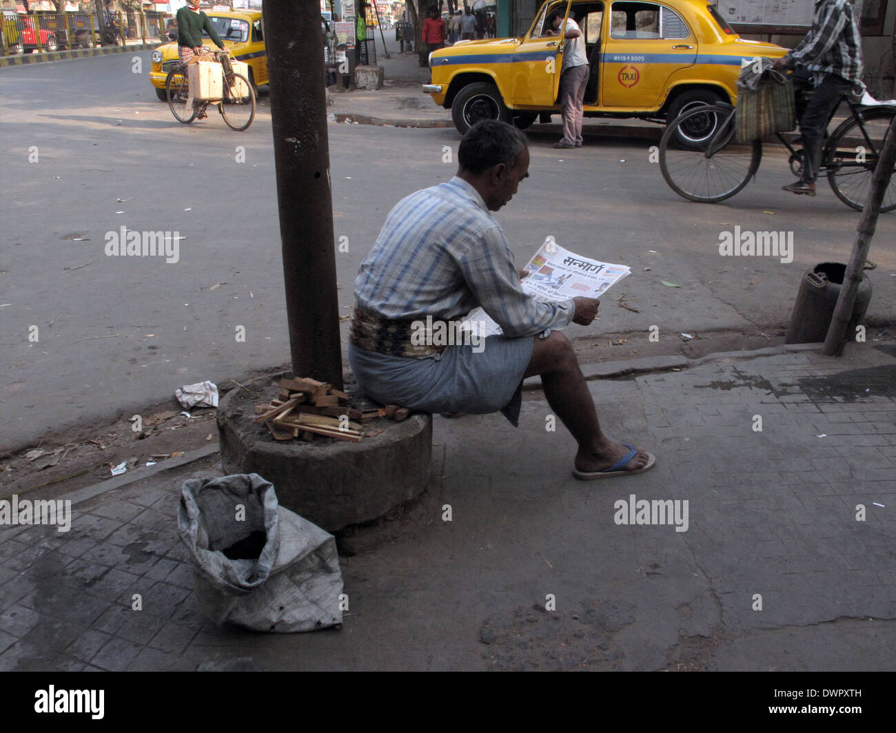 Rues de Calcutta, l'homme lisant le journal tout en ignorant tout autour de lui, à Kolkata, Inde Banque D'Images