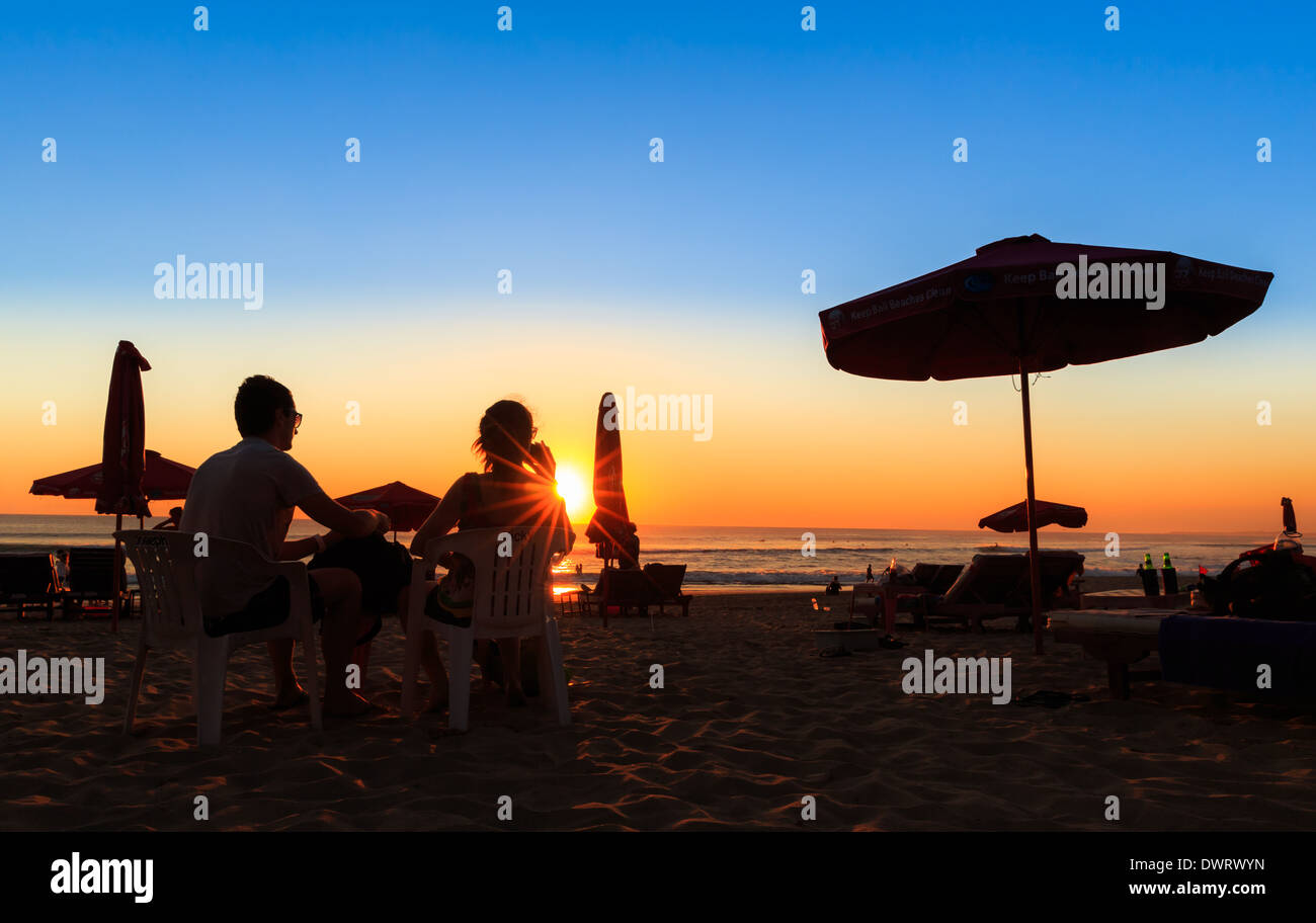 Un couple assis sur la plage au coucher du soleil, de la plage de Sanur, Bali, Indonésie Banque D'Images