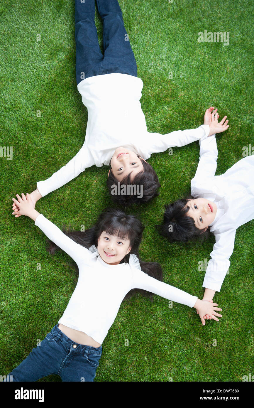 Trois enfants allongés sur l'herbe Banque D'Images