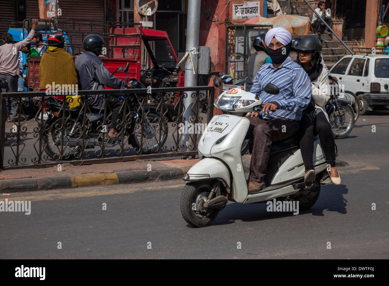 Jaipur, Rajasthan, Inde. Le trafic de la rue de la mi-journée dans le centre de Jaipur. Conducteur et passager Moto Sikh. Banque D'Images