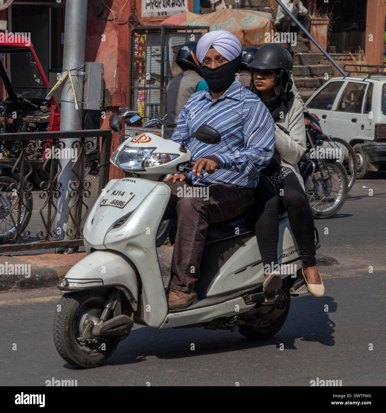Jaipur, Rajasthan, Inde. Le trafic de la rue de la mi-journée dans le centre de Jaipur. Conducteur et passager Moto Sikh. Banque D'Images