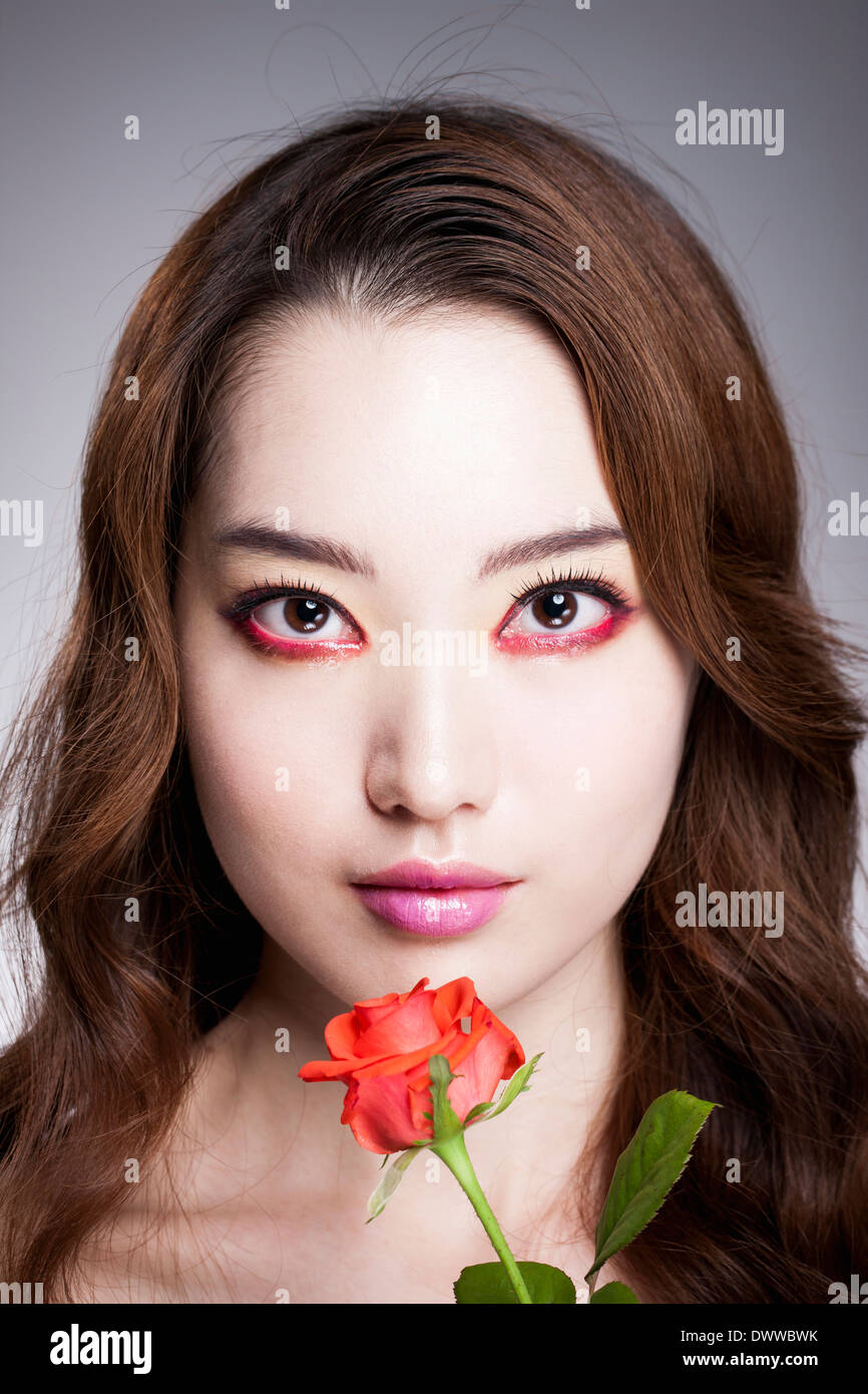 Une femme avec du maquillage et rouge une rose Banque D'Images