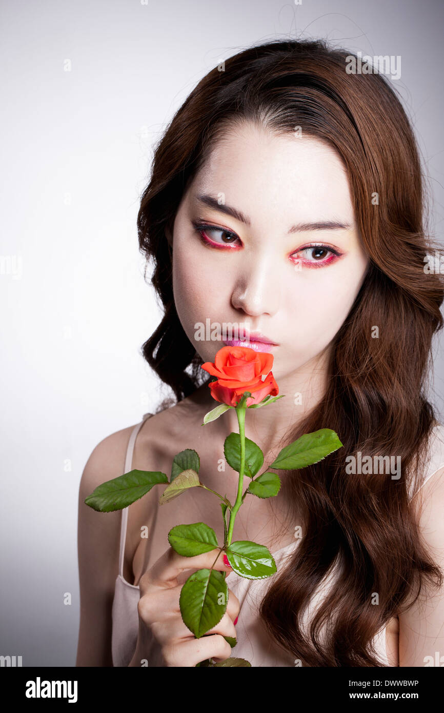 Une femme avec du maquillage et rouge une rose Banque D'Images