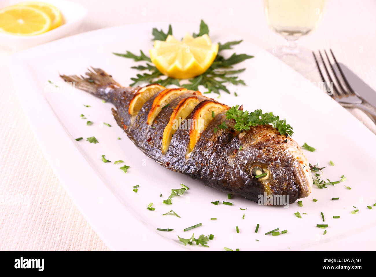 La dorade grillée poisson, citron, roquette sur plaque blanche, Close up Banque D'Images