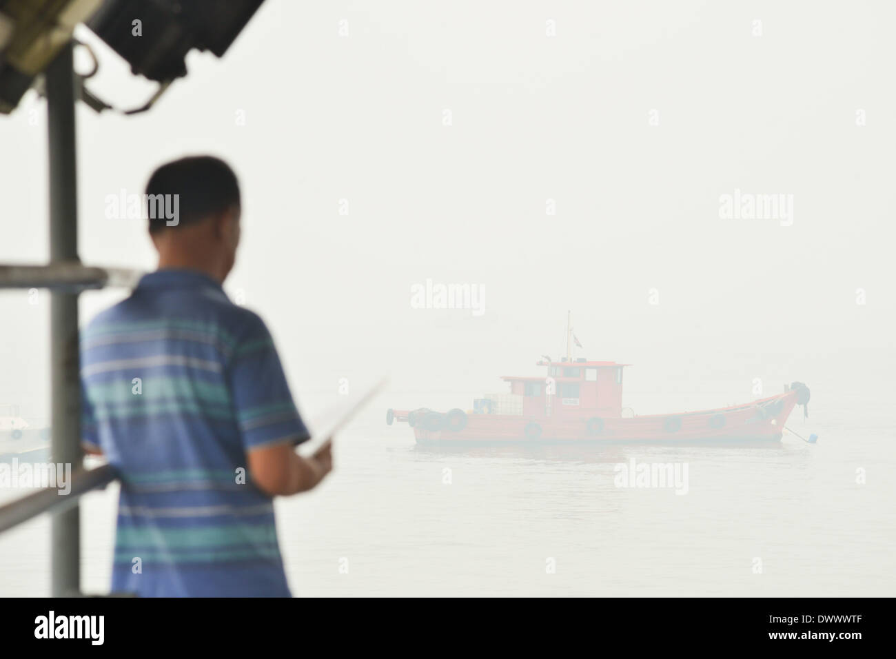 Selangor, Malaisie. 14 mars, 2014. Un touriste attend à bord d'un bateau à Port Klang, Malaisie, le 14 mars 2014. Les écoles sont fermées le vendredi à cause de l'insalubrité de l'air. Les polluants de l'air index (API) de Port Klang, située à l'ouest de la capitale, Kuala Lumpur, a frappé le vendredi niveau malsain, selon le site web du ministère de l'environnement de la Malaisie. (Xinhua/Chong Voon Chung) (lmz) Banque D'Images