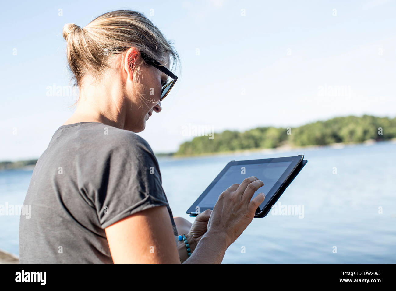 Mid adult woman using digital tablet by lake Banque D'Images