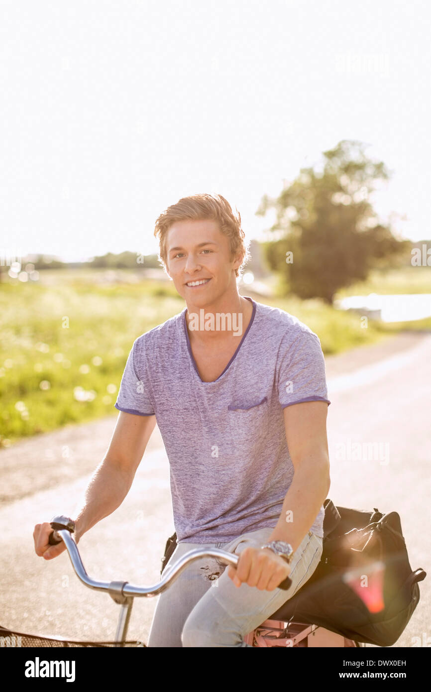 Portrait of happy young man cycling on country road Banque D'Images