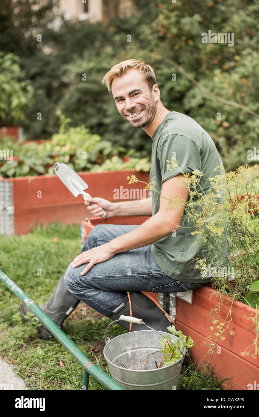 Portrait de l'homme heureux avec équipement de jardinage assis dans le  jardin Photo Stock - Alamy