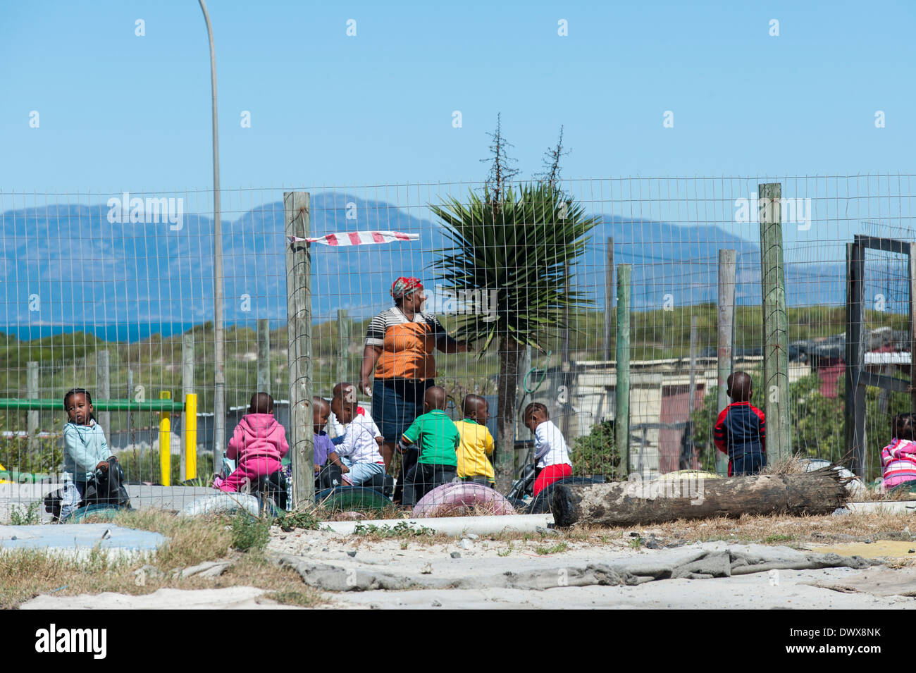 Les enfants et jouer à l'extérieur de l'enseignant d'une école maternelle à Khayelitsha, Cape Town, Western Cape, Afrique du Sud Banque D'Images