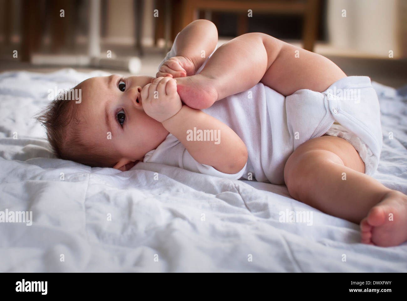 Bébé avec ses pieds dans sa bouche Banque D'Images