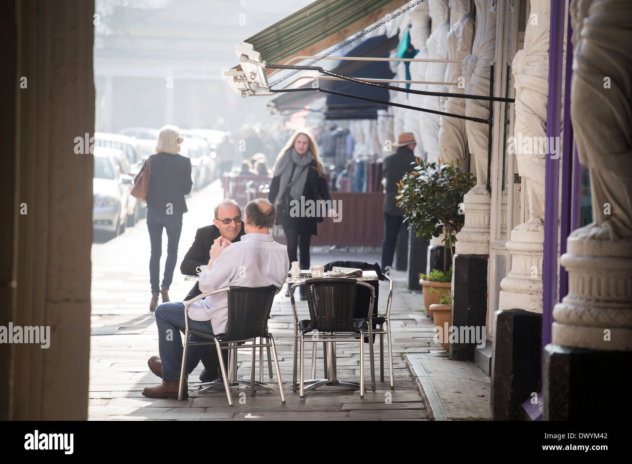 Deux hommes assis à l'extérieur à la terrasse d'un café sur la rue de Montpellier à Cheltenham, Royaume-Uni Banque D'Images