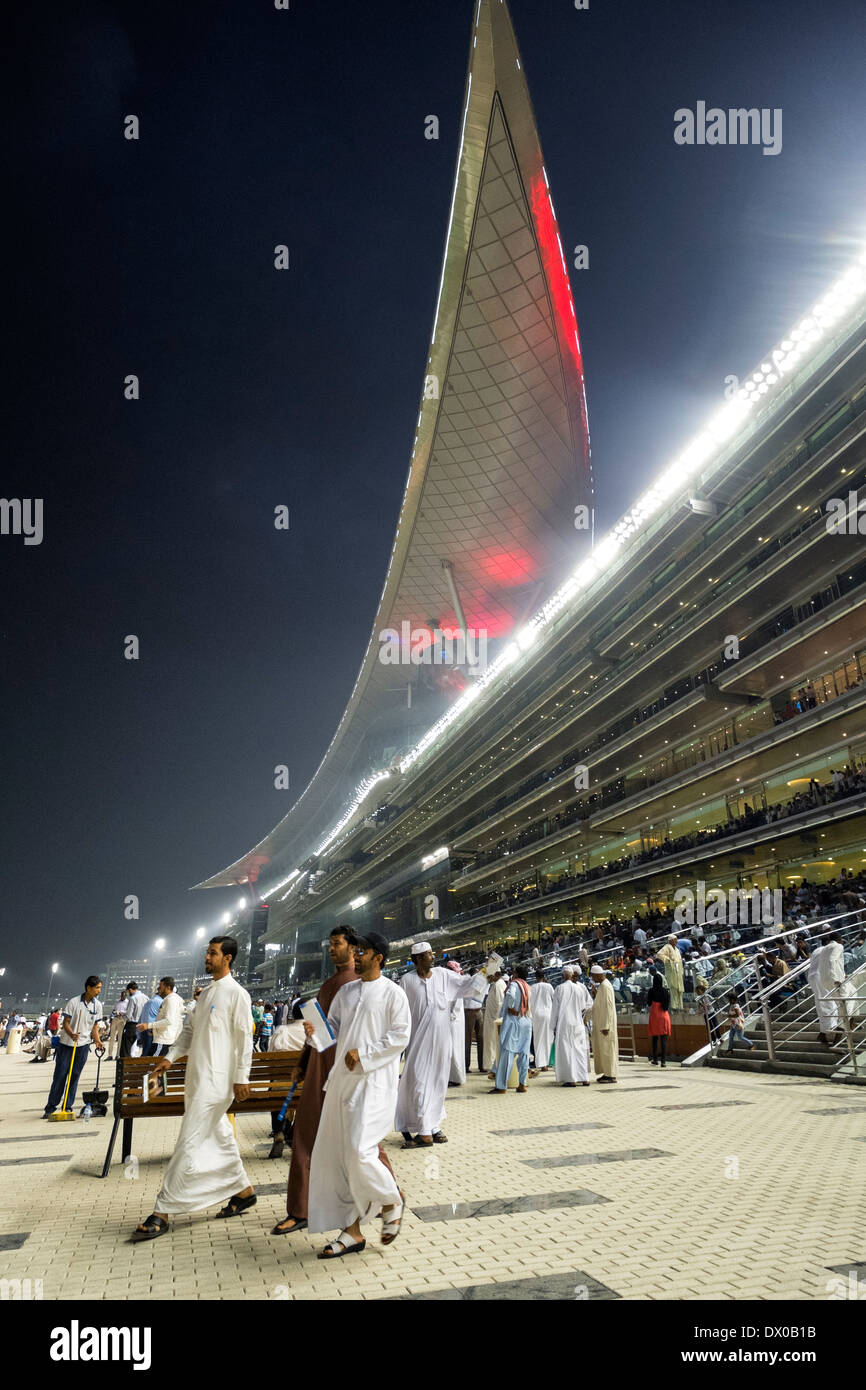 Les spectateurs et les courses de chevaux à la tribune réunion à l'hippodrome de Meydan Al nuit à Dubaï Émirats Arabes Unis Banque D'Images