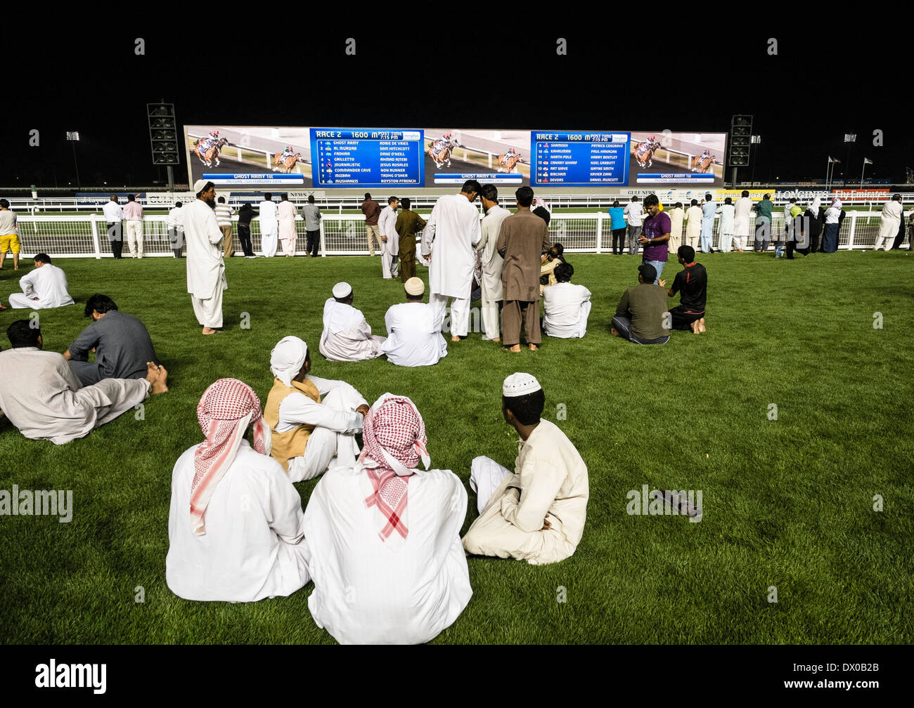 Les spectateurs à regarder course à la course de chevaux à l'hippodrome de Meydan al réunion de nuit à Dubaï Émirats Arabes Unis Banque D'Images