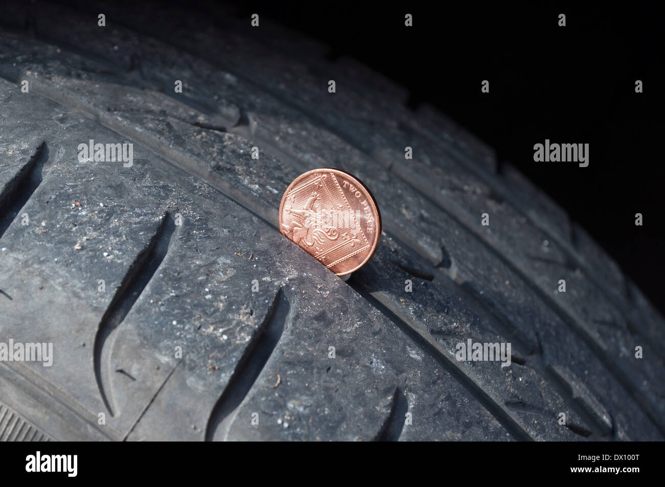 Vérifier la profondeur des sculptures d'un pneu de voiture à l'aide d'un coin Banque D'Images