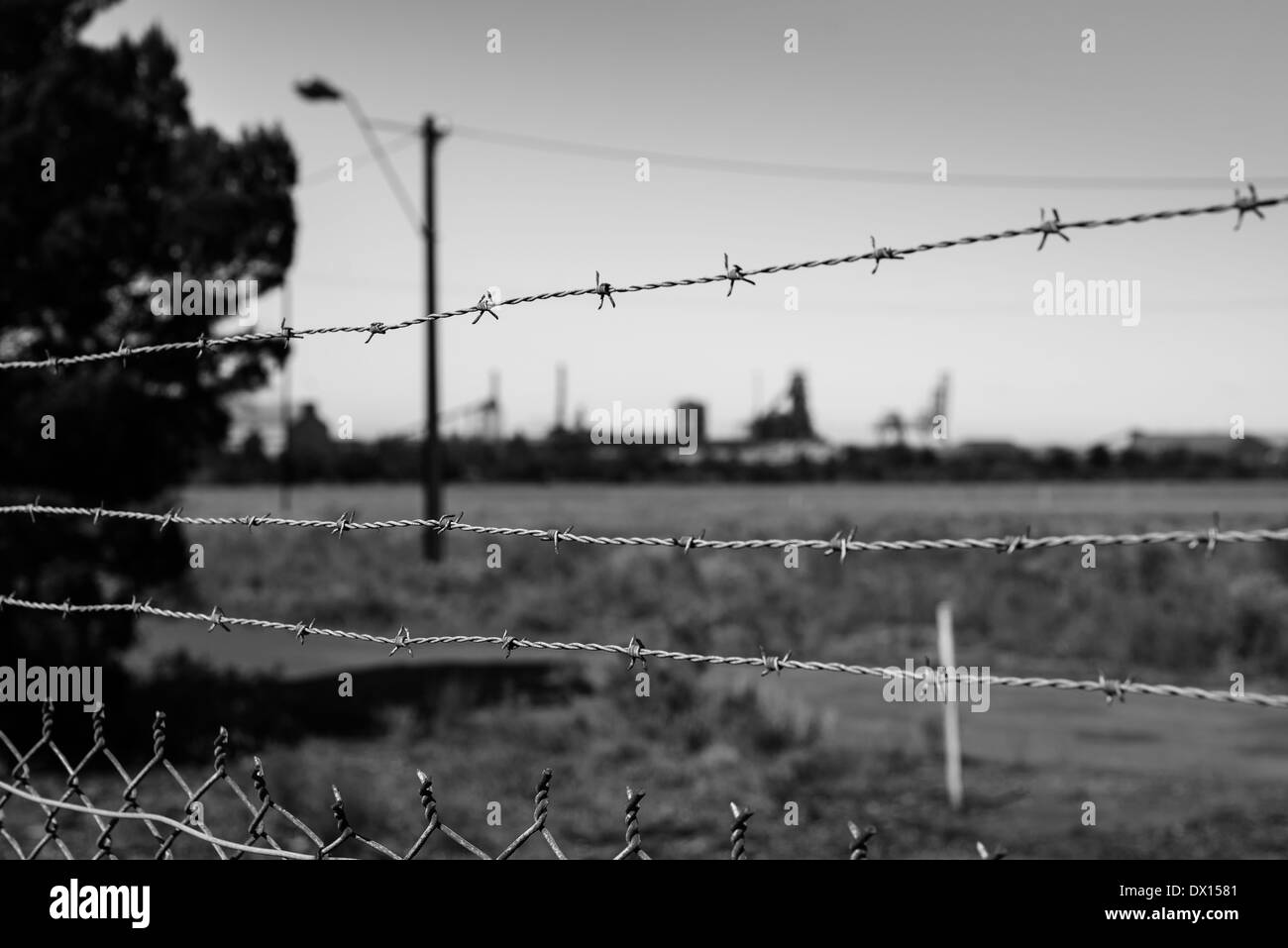 Terrain industriel hors foyer, derrière des barbelés, en noir et blanc. Banque D'Images