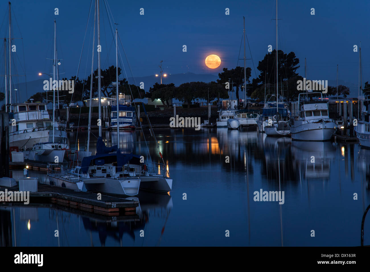 Le paramètre Worm Pleine Lune reflétée dans le San Leandro Marina. Banque D'Images