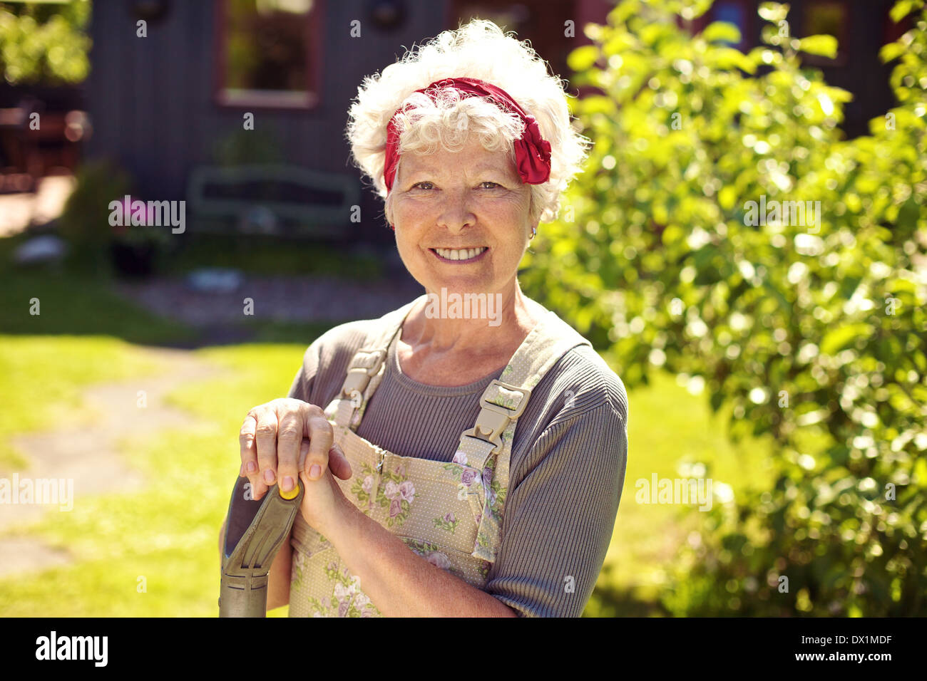 Portrait of happy senior couple permanent d'outils de jardinage dans le jardin Banque D'Images