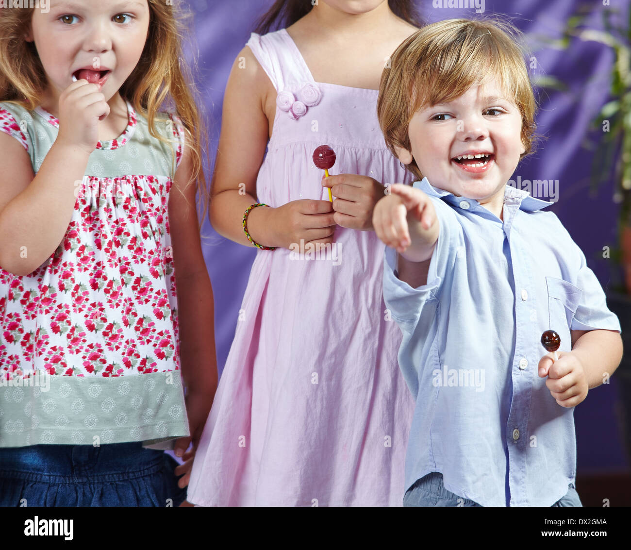 Happy boy with lollipop pointant avec le doigt dans un jardin Banque D'Images