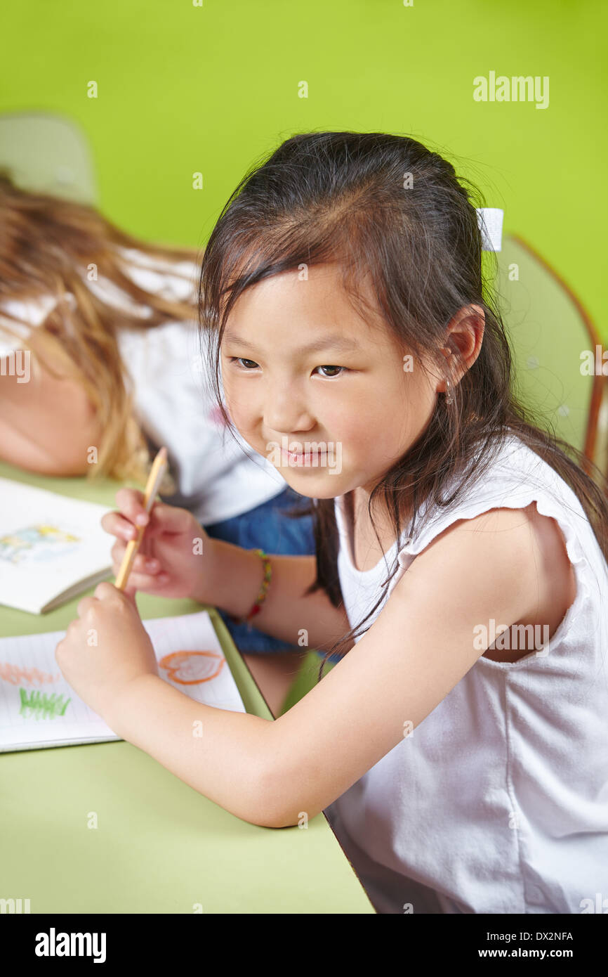 Chinese girl dessin avec des crayons de couleur dans un jardin d'group Banque D'Images