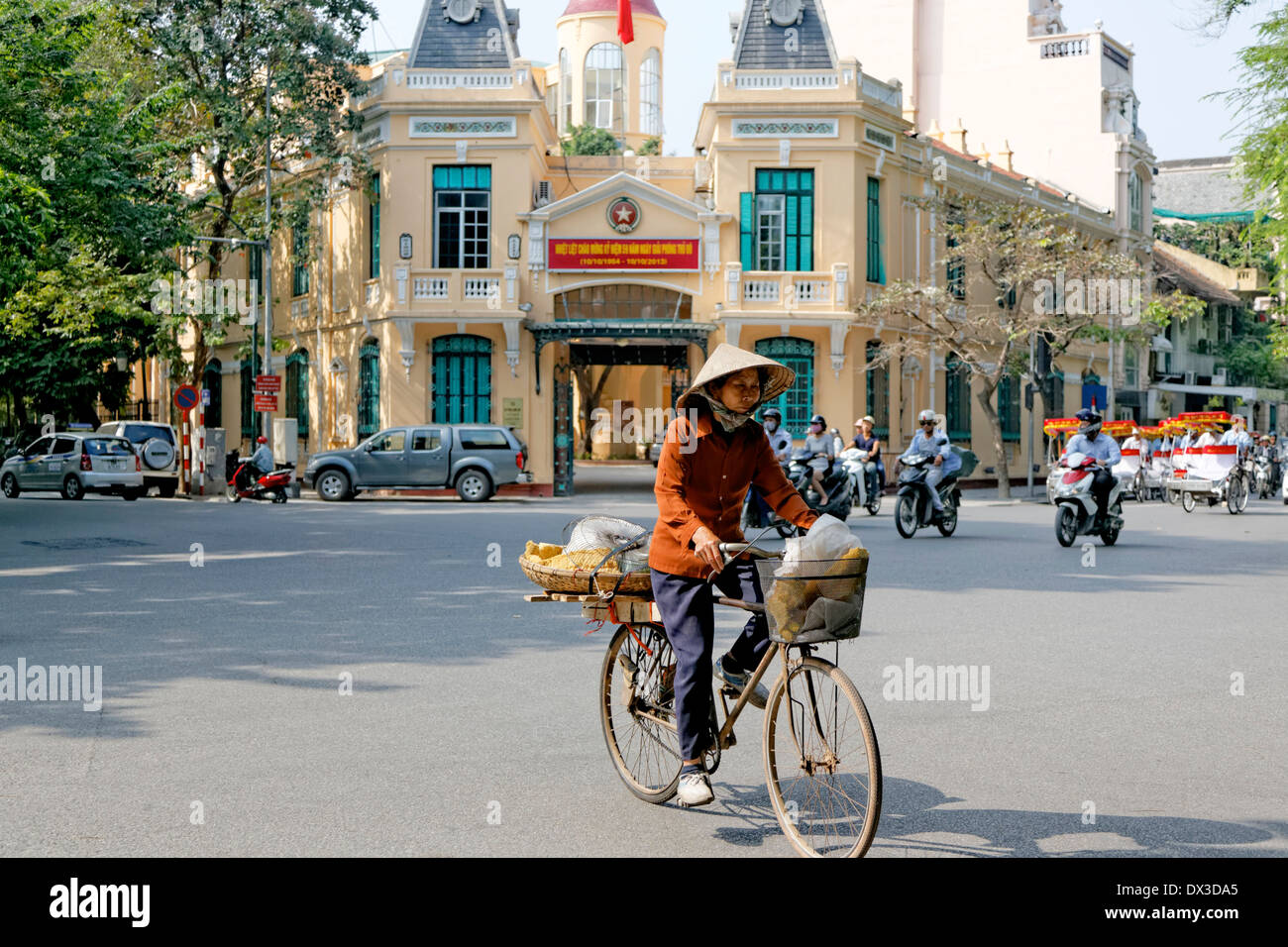 Cycliste avec femme asiatique traditionnel hat souvent appelé un coolie hat défiler à Hanoi Banque D'Images