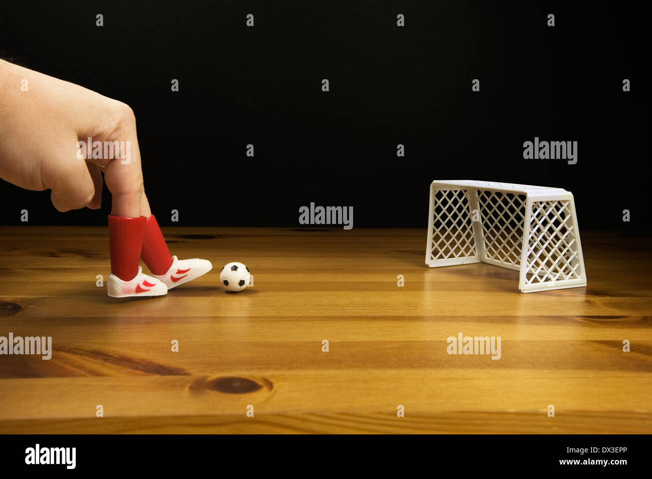 Les doigts d'une personne dans le plastique Chaussures de foot de table de jeu de football sur une table en bois, Banque D'Images