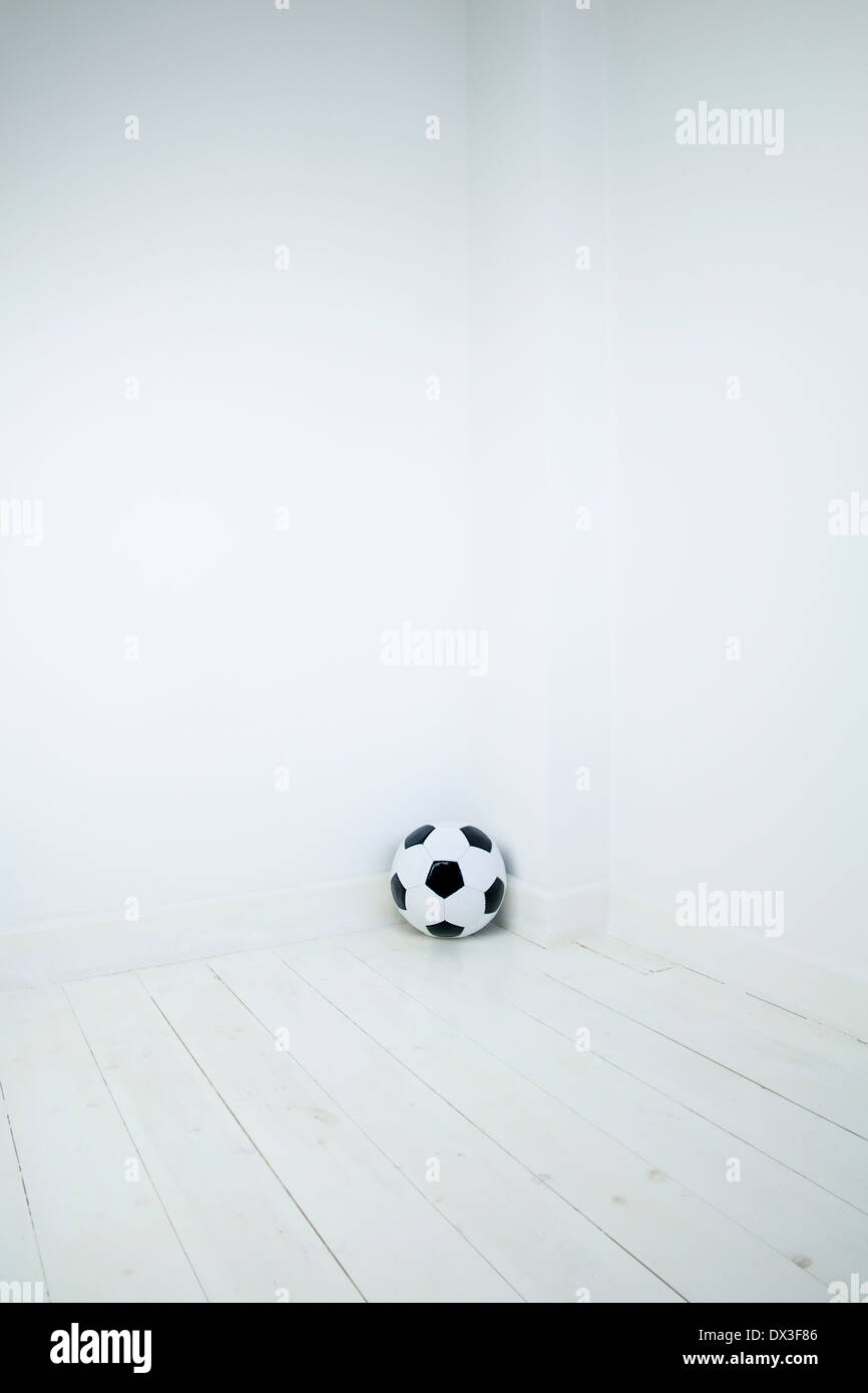 Football en cuir noir et blanc dans le coin d'une salle vide Banque D'Images