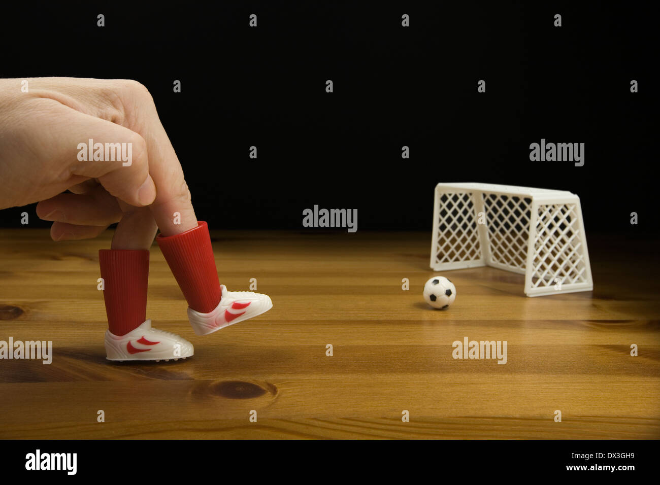 Les doigts d'une personne dans le plastique Chaussures de foot de table de jeu de football sur une table en bois, Banque D'Images