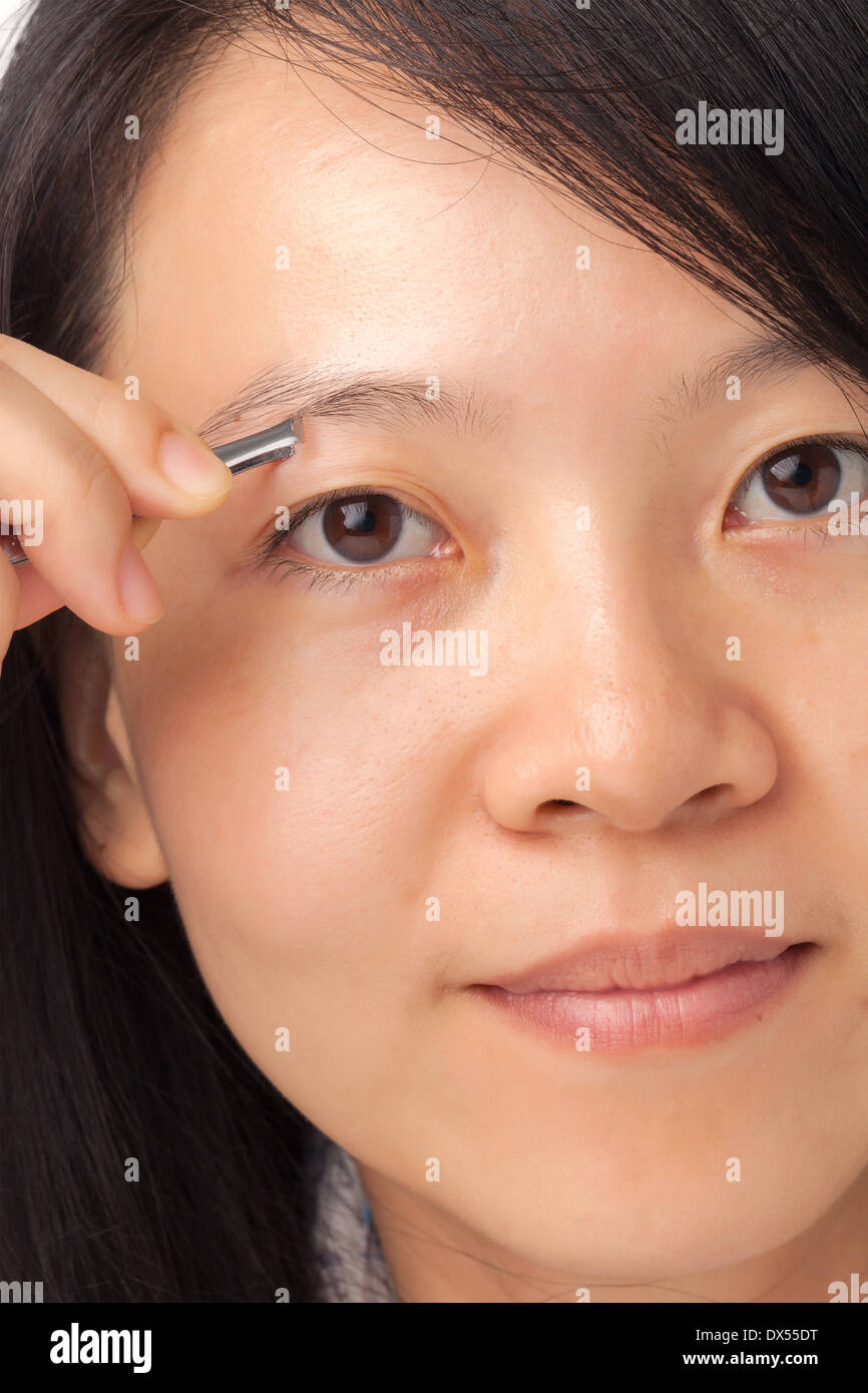 Woman plucking her eyebrows with tweezers Banque D'Images