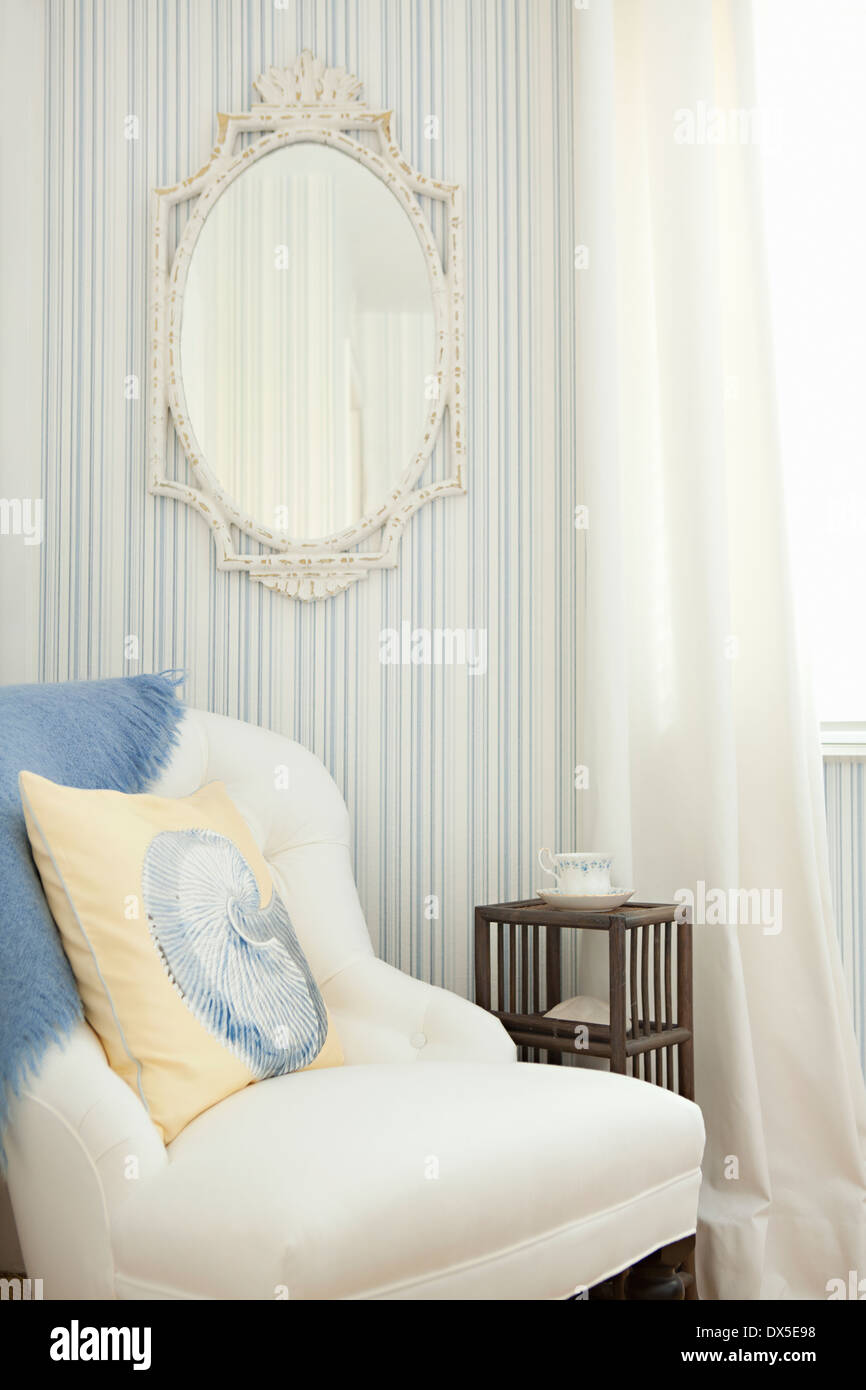 Miroir sur le mur au-dessus de fauteuil rayé de bleu et blanc chambre Banque D'Images
