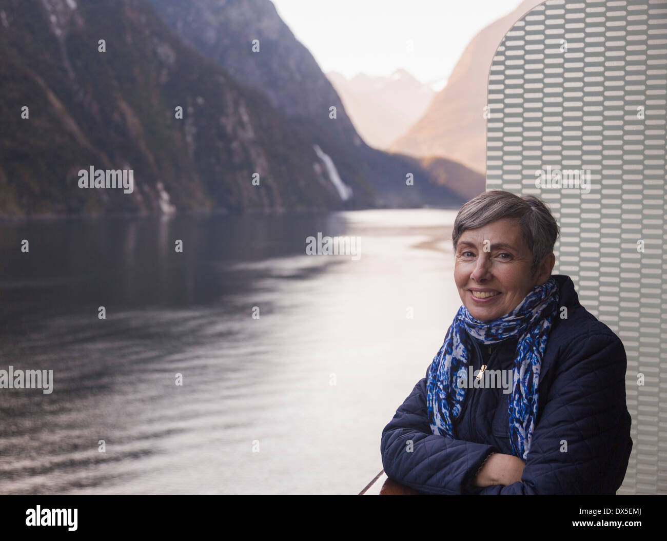 Hauts femme debout sur le pont d'un bateau de croisière, Milford Sound, Nouvelle Zélande tôt le matin Banque D'Images