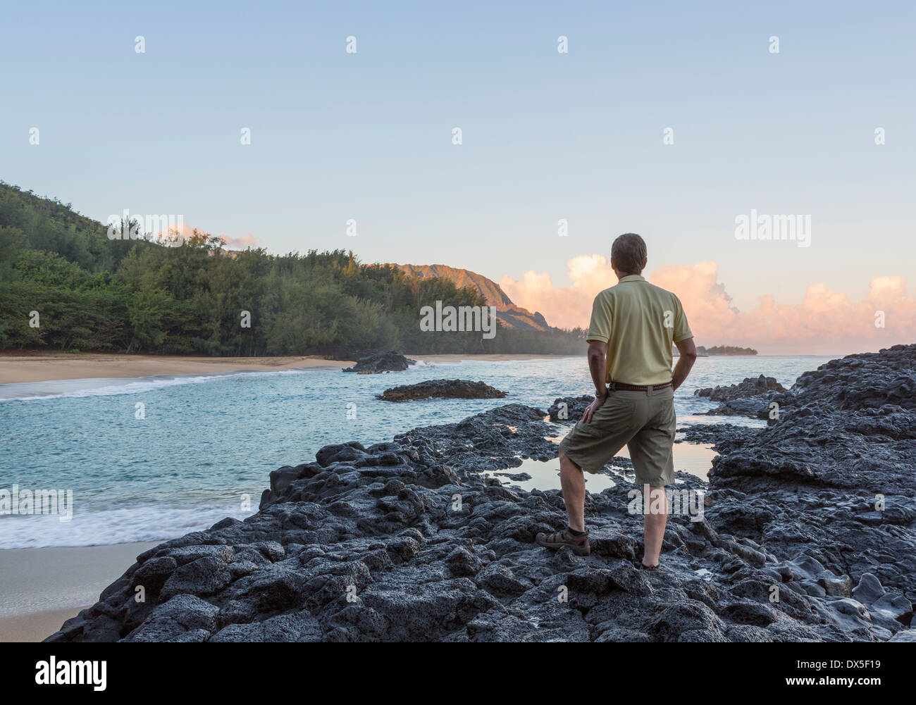 L'homme donne sur les rochers et l'océan à Lumahai Beach à Kauai, Hawaii, USA à l'aube Banque D'Images