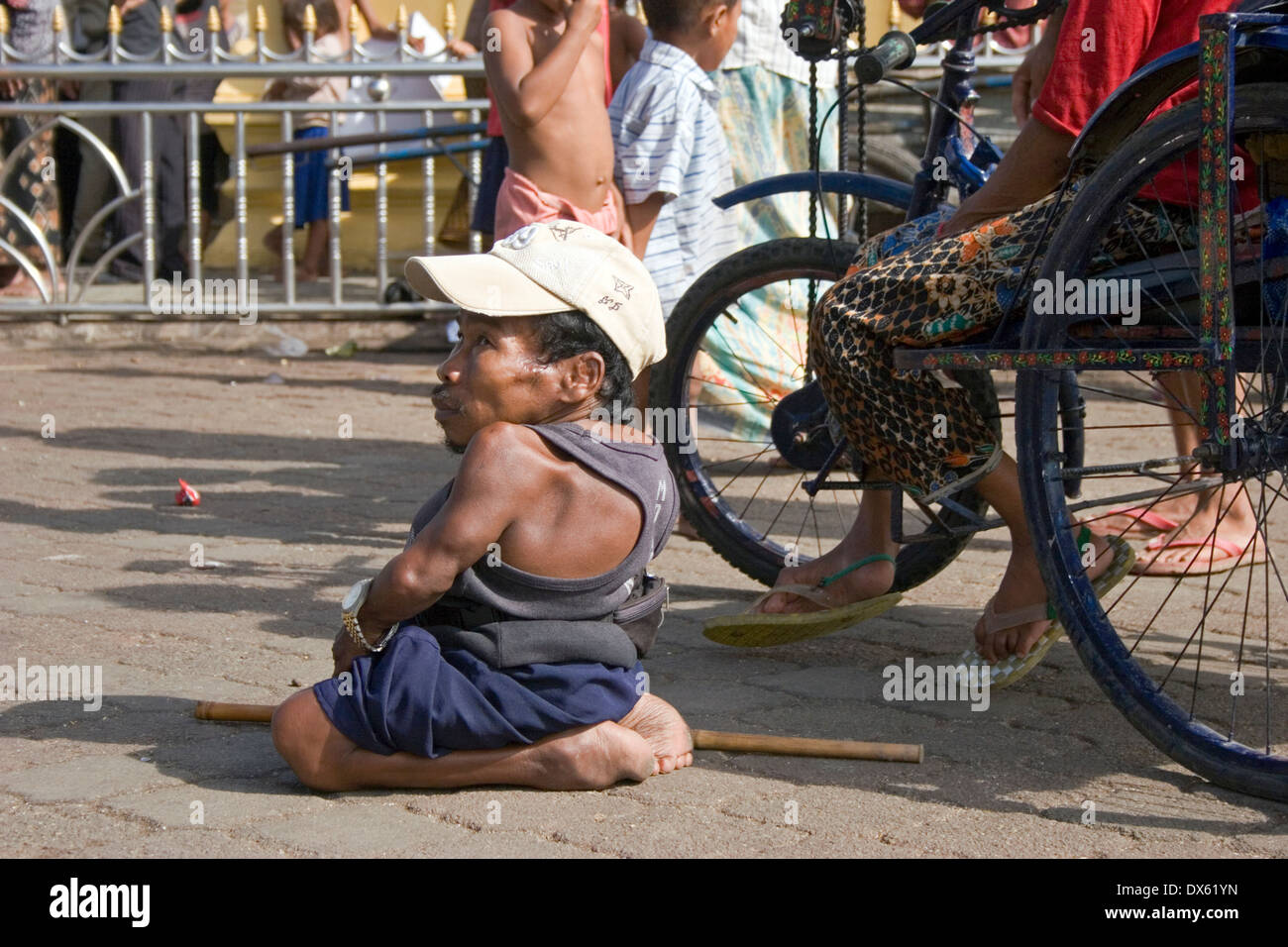Un homme handicapé est assis sur le sol près d'une personne handicapée en fauteuil roulant à Phnom Penh, Cambodge. Banque D'Images