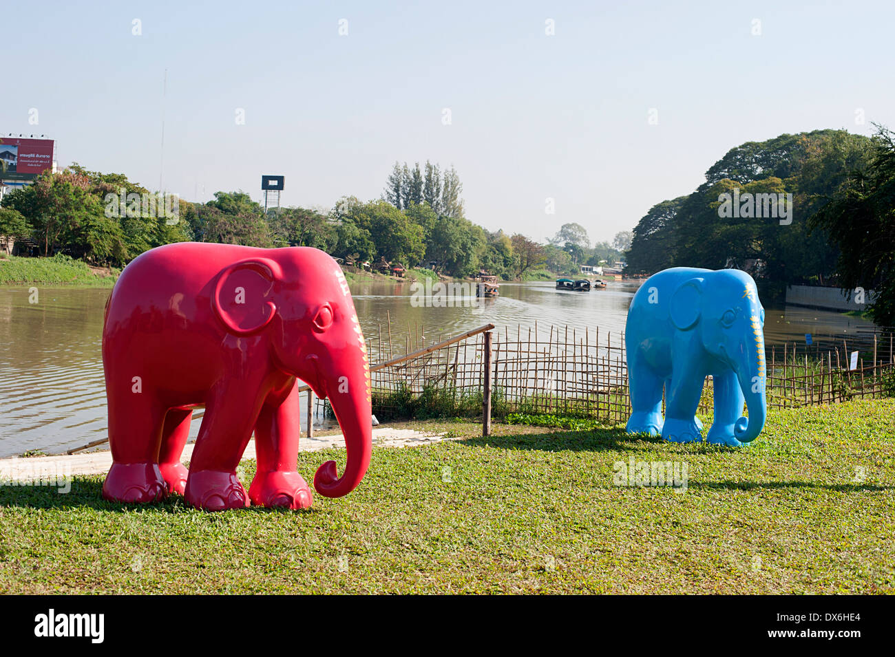 Statues d'éléphant bleu et rouge debout sur la pelouse d'un restaurant en face de la rivière Ping à Chiang Mai. Banque D'Images