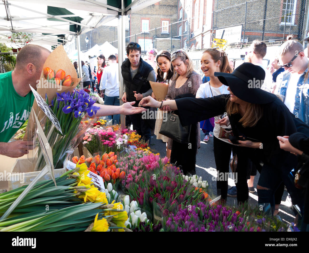 Femme payant avec l'argent comptant acheter des tulipes de printemps de bulbe coupé fleurs commerçant Columbia Road Flower Market East London E2 Angleterre UK KATHY DEWITT Banque D'Images