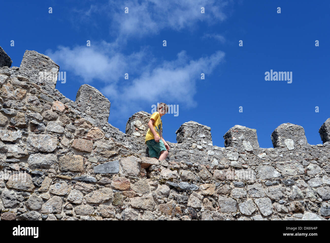 Garçon escalade un mur de château, Sintra, Portugal. Banque D'Images