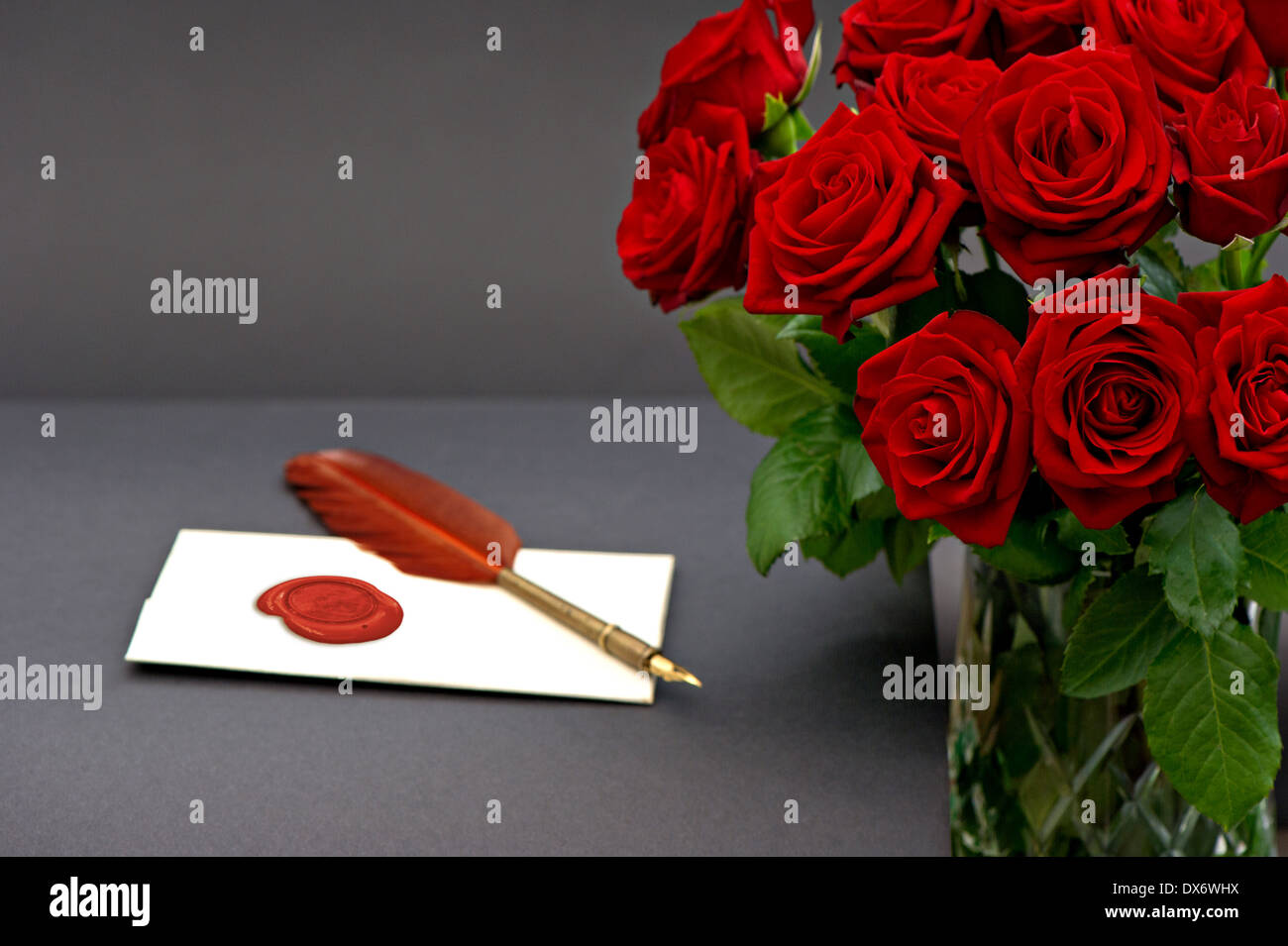 Bouquet de roses rouges et de lettre d'amour sur fond noir de fleurs de fête. Banque D'Images