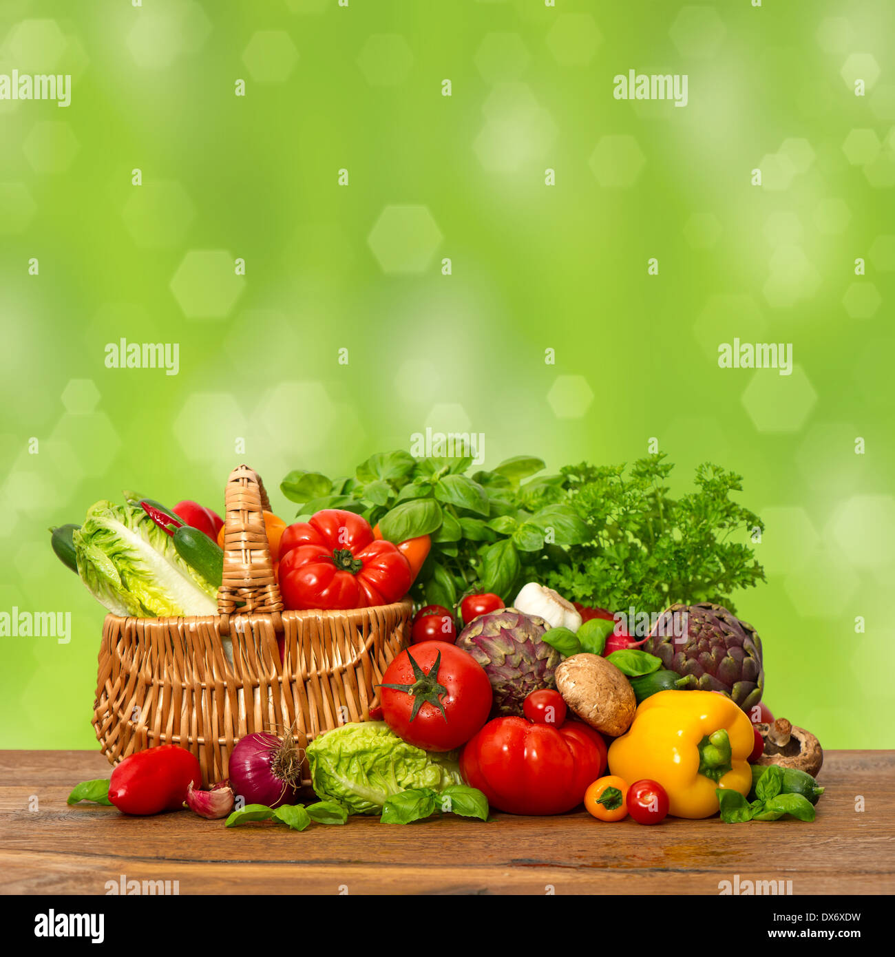 Des légumes frais et des herbes sur la table en bois au-dessus de la nature fond vert. aliments crus ingrédients. panier Banque D'Images