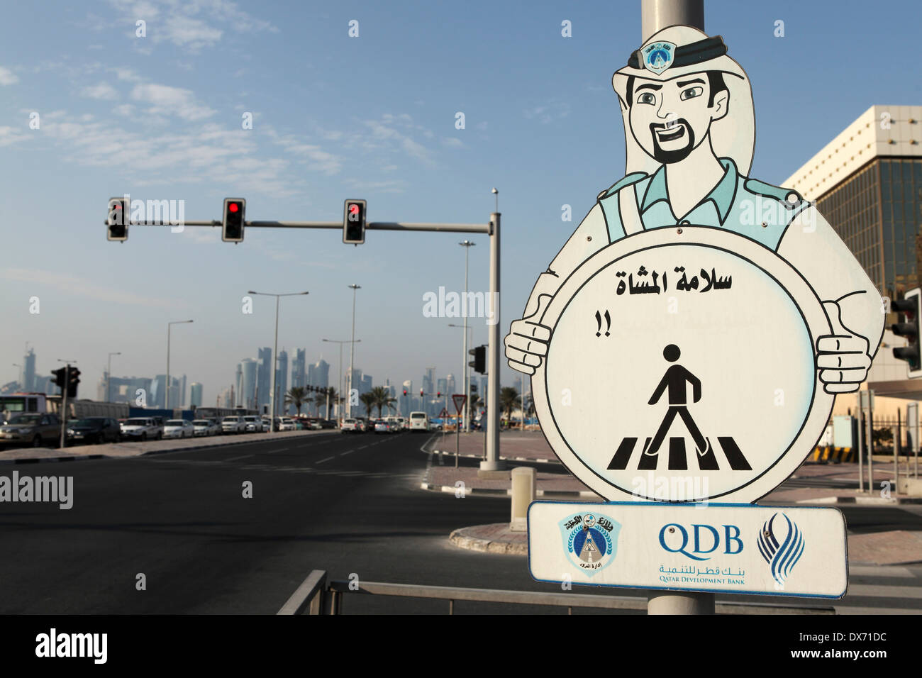 Un signe appelle à la prudence en traversant la route à Doha, Qatar. Banque D'Images