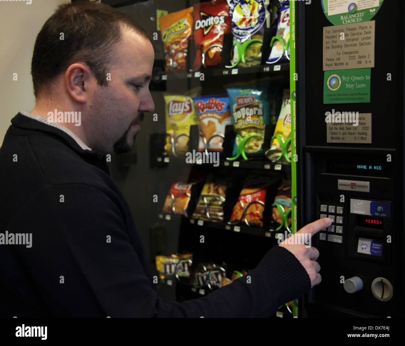 L'achat d'un homme junk food snack dans une machine distributrice, New York, USA Banque D'Images