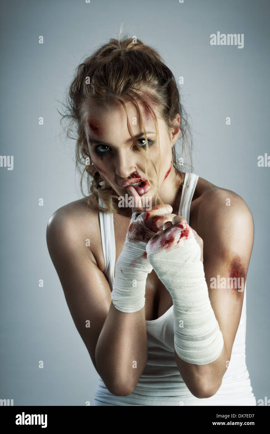 Une photo de femme debout en position de combat avec du sang sur le visage et les poings. Banque D'Images