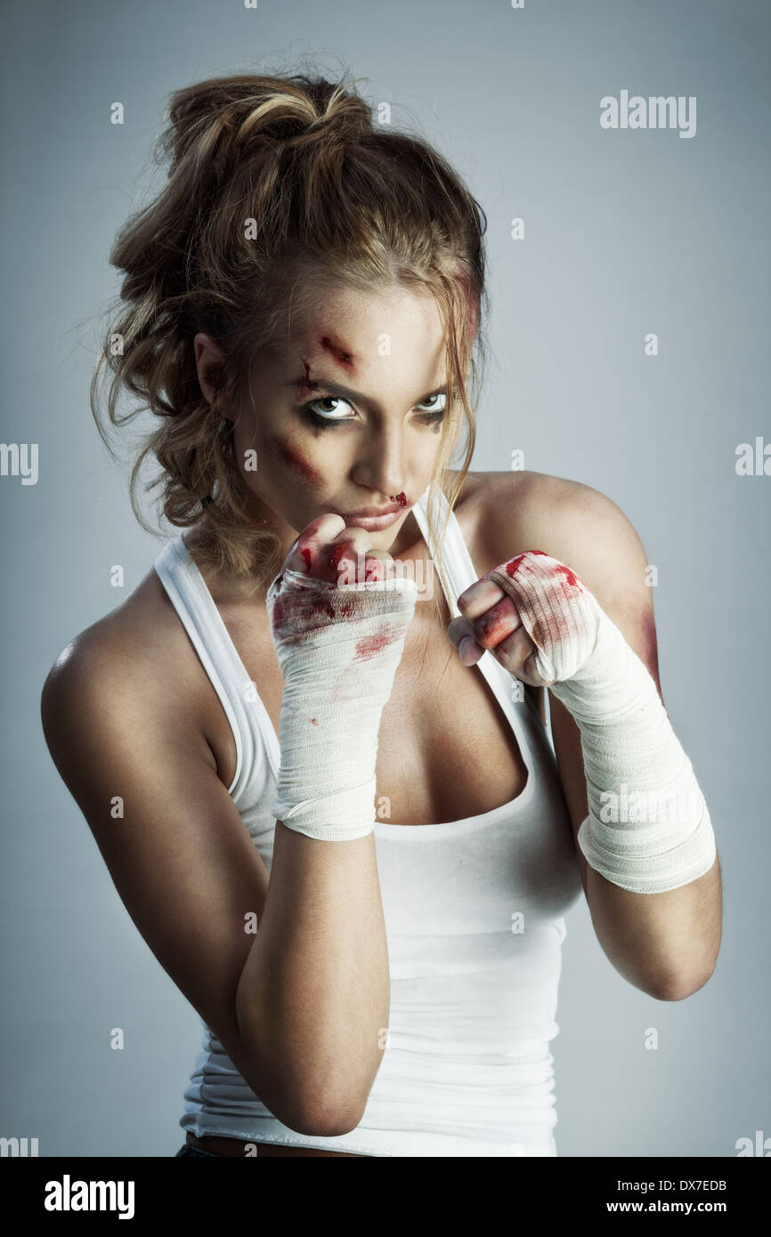 Une photo de femme debout en position de combat avec du sang sur le visage et les poings. Banque D'Images