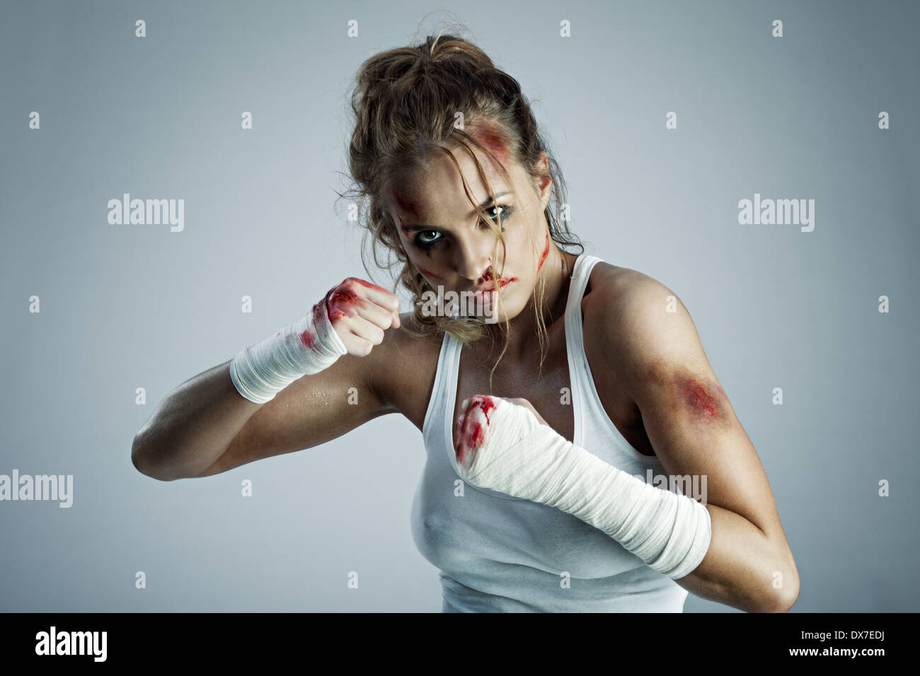 Une photo de femme debout en position de combat avec du sang sur le visage et les poings. Banque D'Images