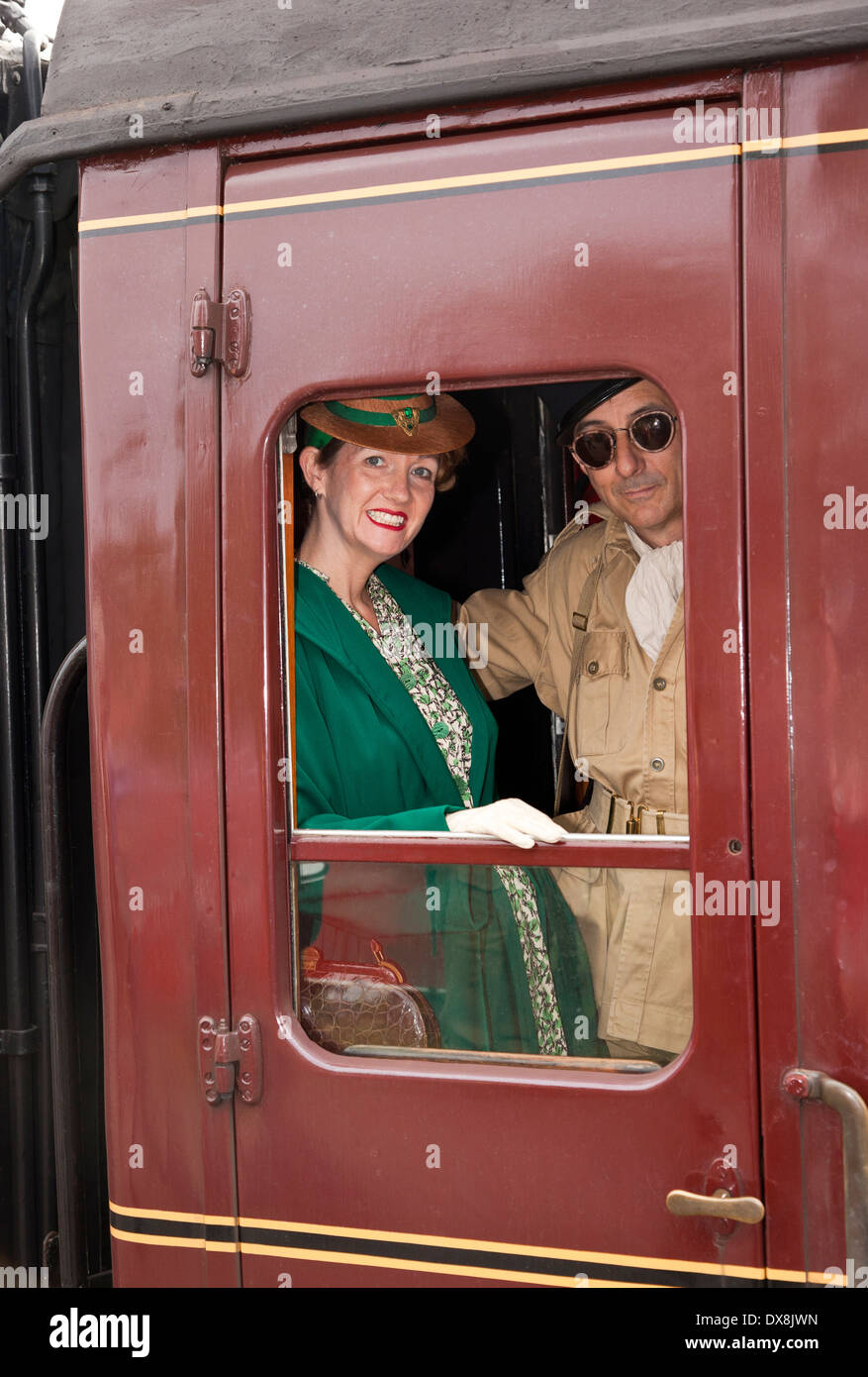 Un couple portant des vêtements des années 1940 à la recherche d'une fenêtre de train Banque D'Images