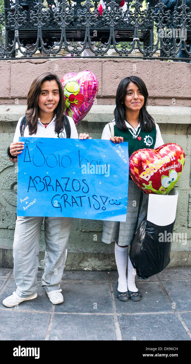 2 jolies filles du secondaire avec de longs cheveux noirs Annoncez gratuitement hugs en face de Zocalo band shell sur Valentines Day 2014 Oaxaca Banque D'Images