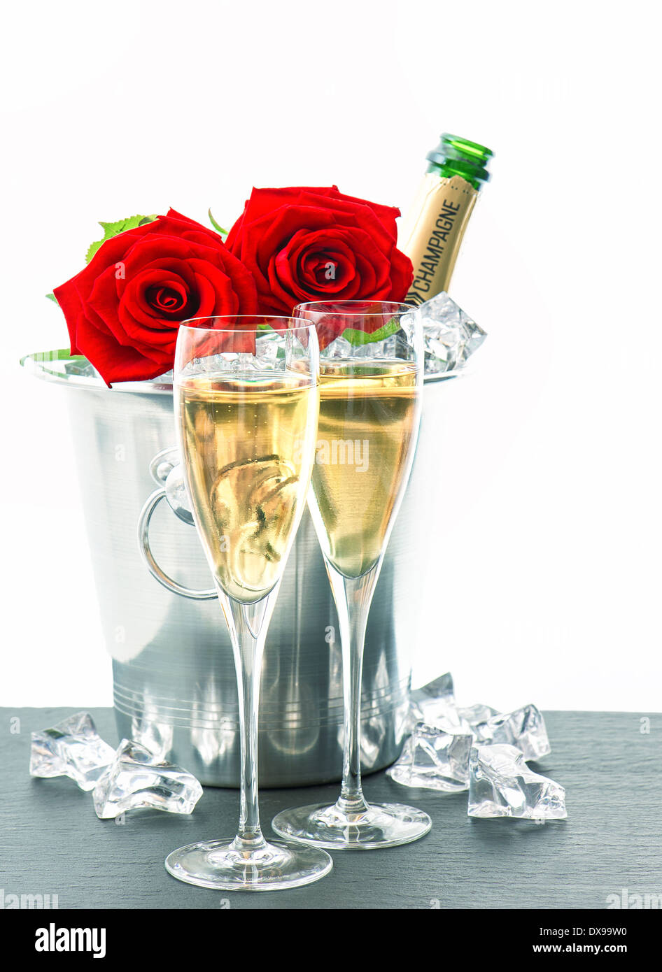 Arrangement de fête avec vin mousseux et fleurs. deux verres, bouteille de champagne et de roses rouges Banque D'Images